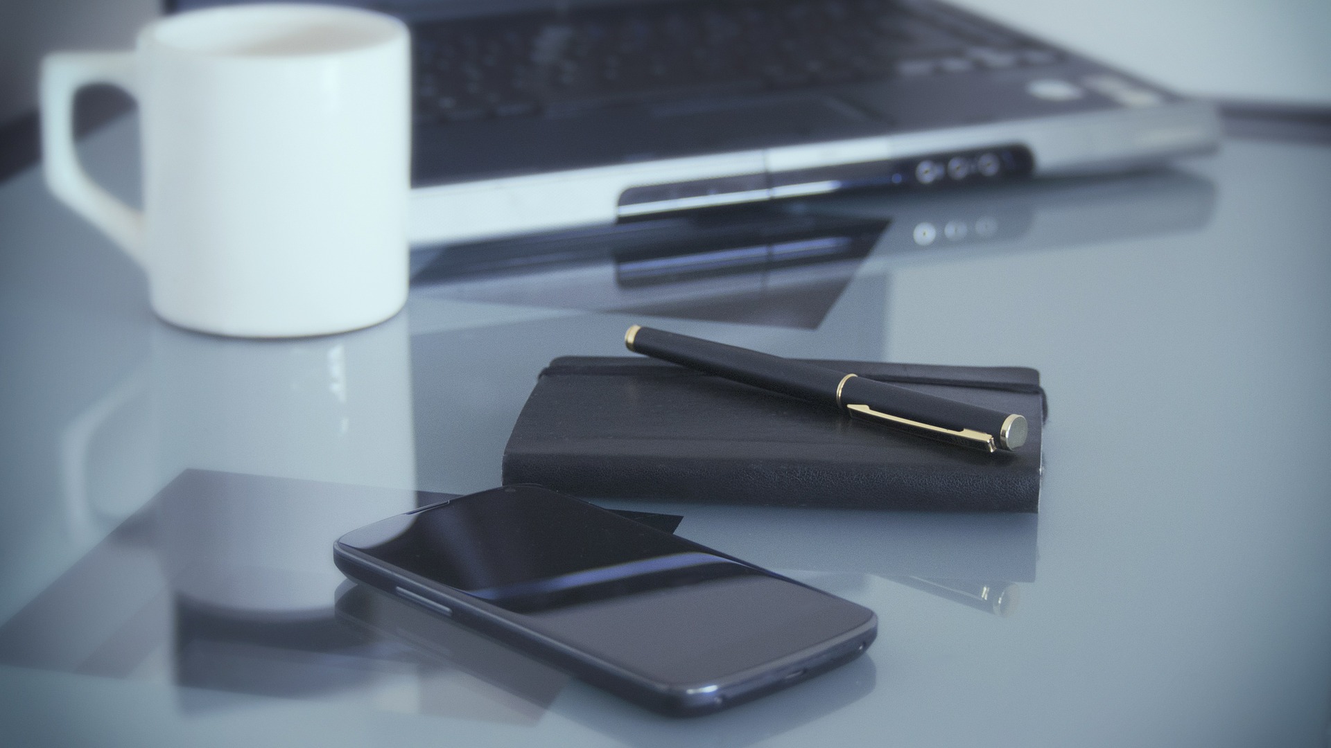 Schreibtisch mit Smartphone, Notizbuch, Laptop und Kaffeetasse
